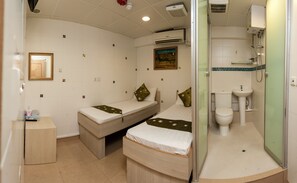 A compact hotel room with two single beds, a small bedside table, a mirror, an air conditioning unit, a toilet, and a shower area. - KG Garden Guest House (Kowloon)