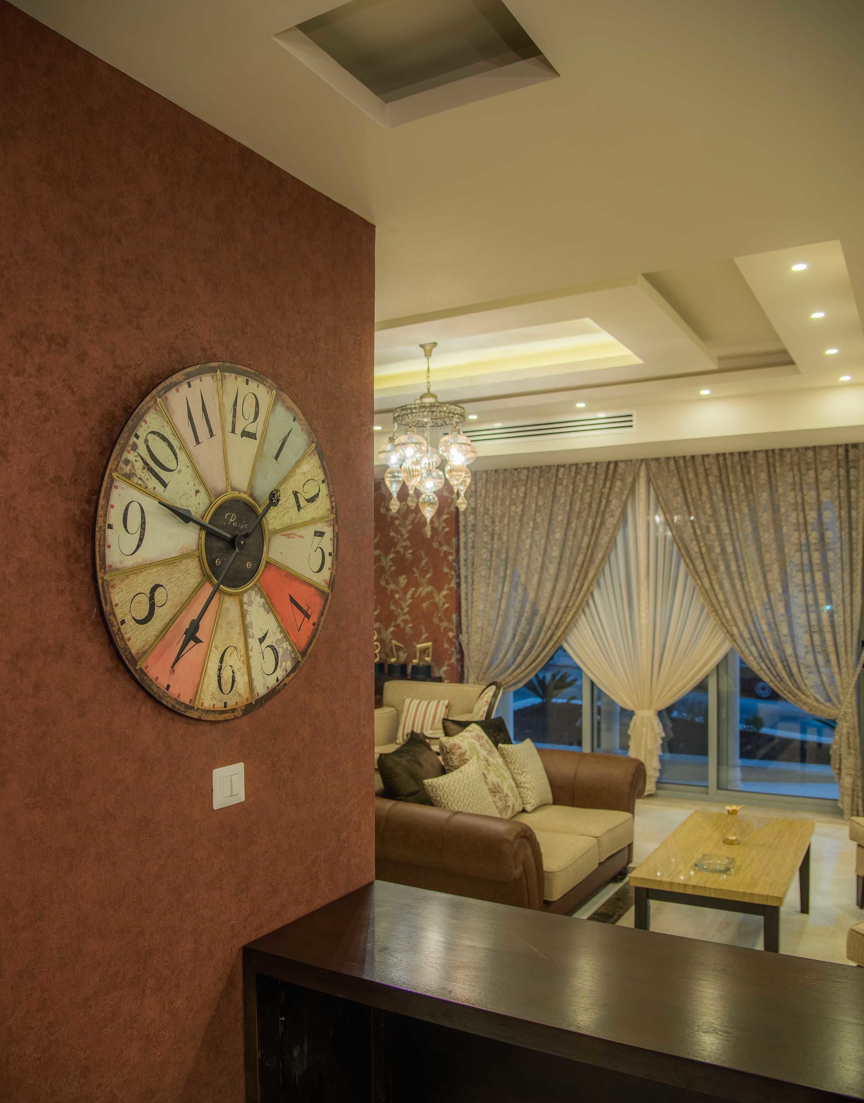Un salon avec une grande horloge murale, un lustre, un canapé et une table basse.