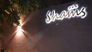 Una pared con la palabra "Shams" iluminada en una fuente cursiva.