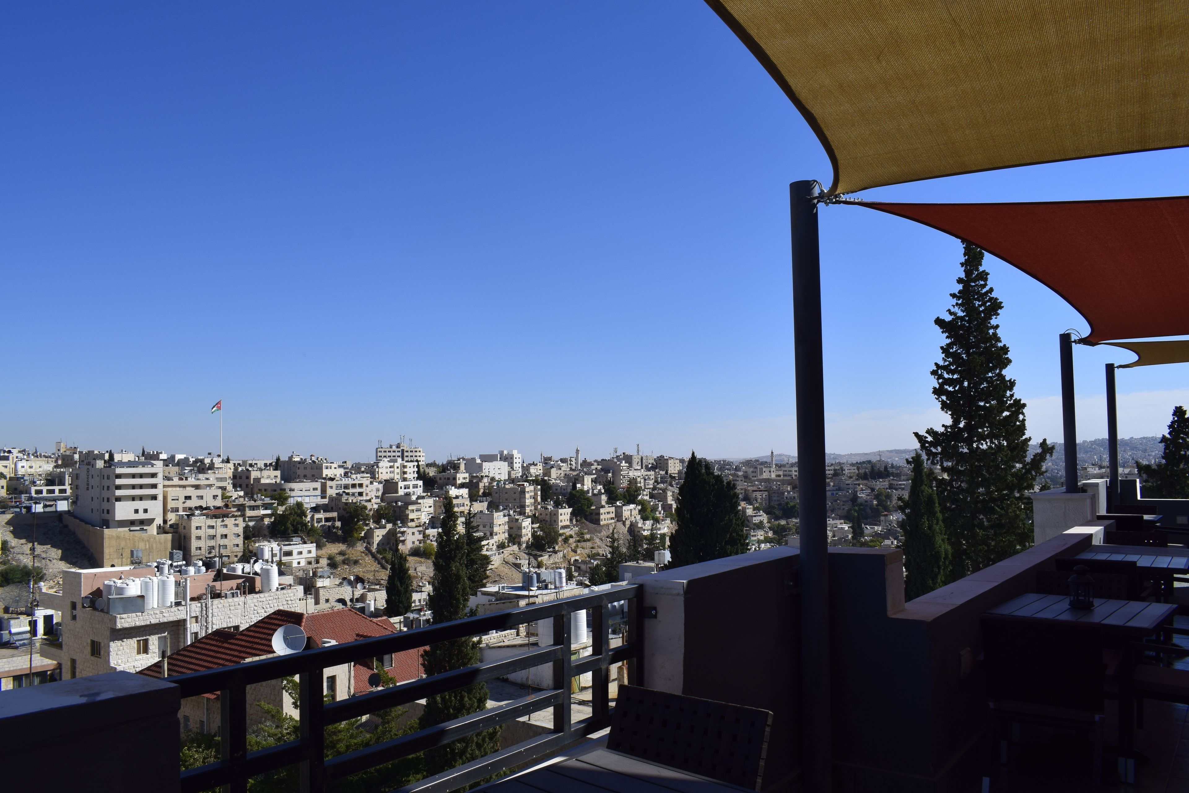 Un balcón con vistas a un paisaje urbano, que incluye edificios y una bandera.