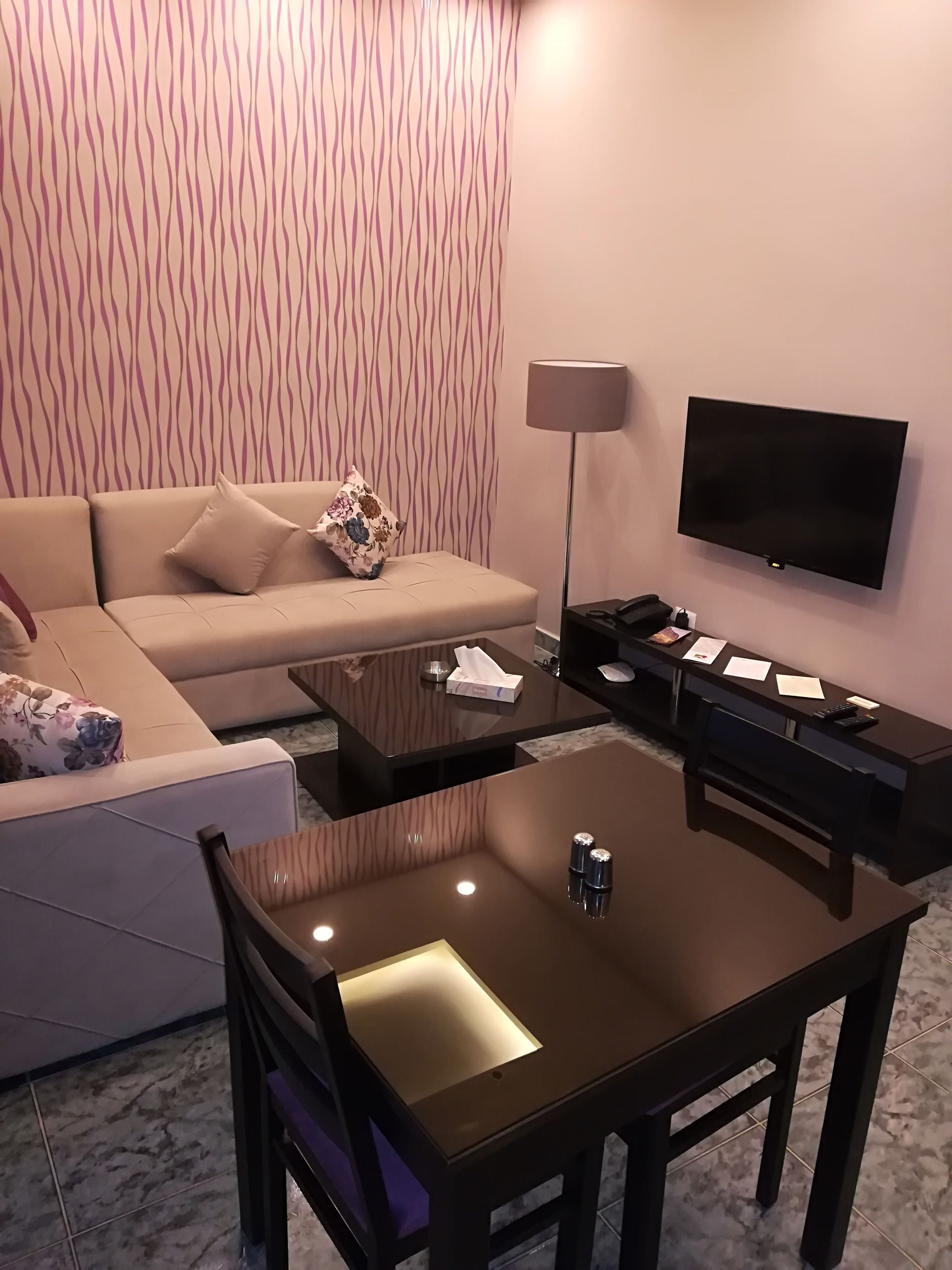 Una sala de estar moderna con un sofá, una mesa de centro, un televisor y una lámpara.