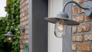 A brick wall with a metal light fixture and a door. - B&B Scheldekant (Oudenaarde)