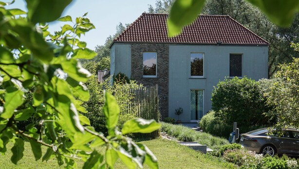 A two-story house with a tiled roof, a front door, and a small garden with a car parked outside. - B&B Scheldekant (Oudenaarde)