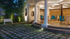 A courtyard with a stone-tiled floor, a white bench, and a seating area with blue chairs and tables. - Epic Unawatuna (Unawatuna)