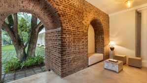 A room with exposed brick walls, a large tree visible through an archway, and a modern lamp. - Epic Unawatuna (Unawatuna)