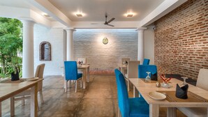 A dining area with a brick wall, white columns, and blue chairs. - Epic Unawatuna (Unawatuna)