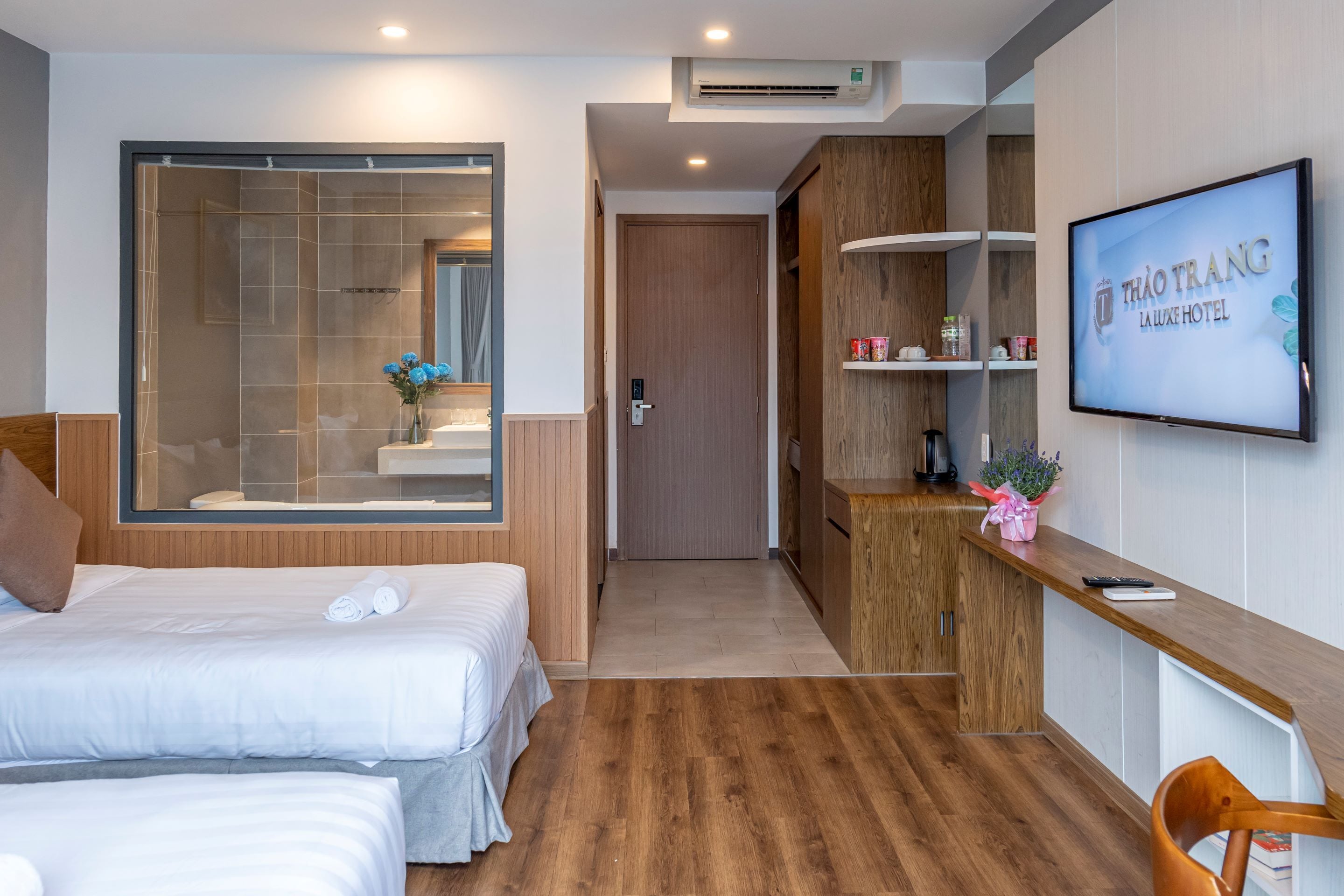 Een hotelkamer met twee bedden, een douche, een televisie en een houten bureau.
