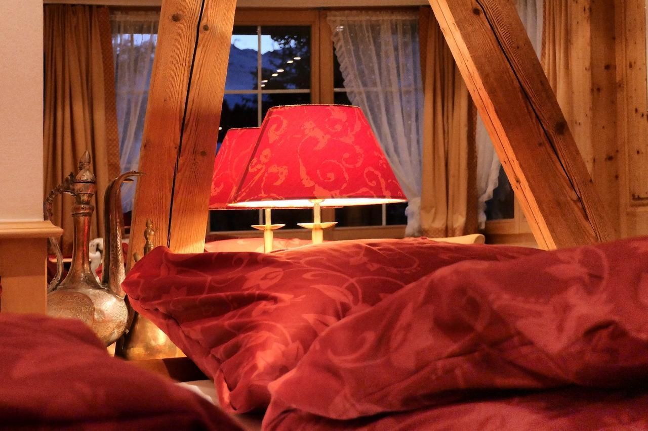 Una habitación con cama, una lámpara roja y una ventana con cortinas.