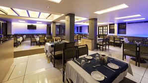 Un restaurante amplio con varias áreas de comedor, cada una con mesas dispuestas para dos.