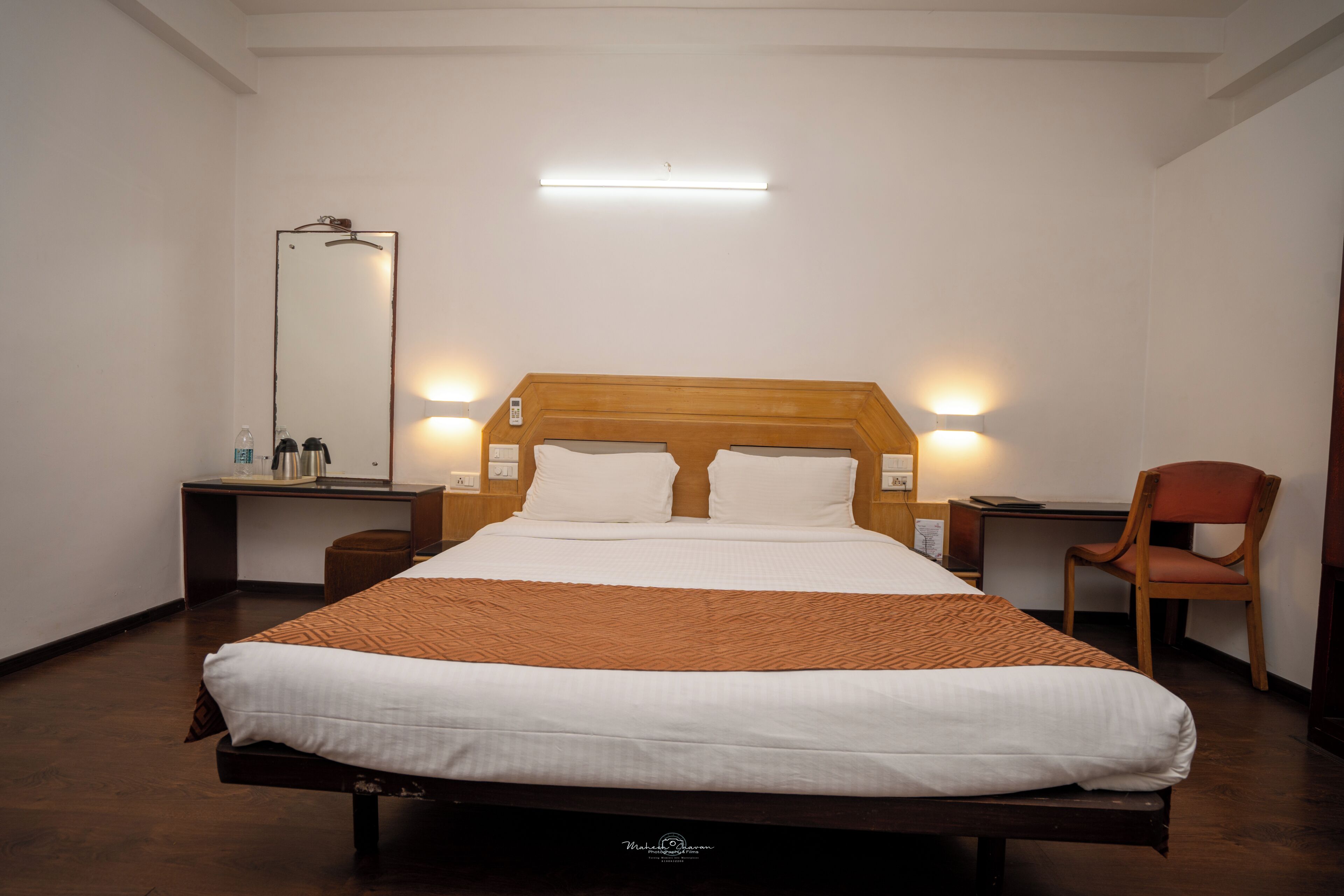 Habitación de hotel con una cama grande, mesitas de noche, un espejo, un escritorio y una silla.