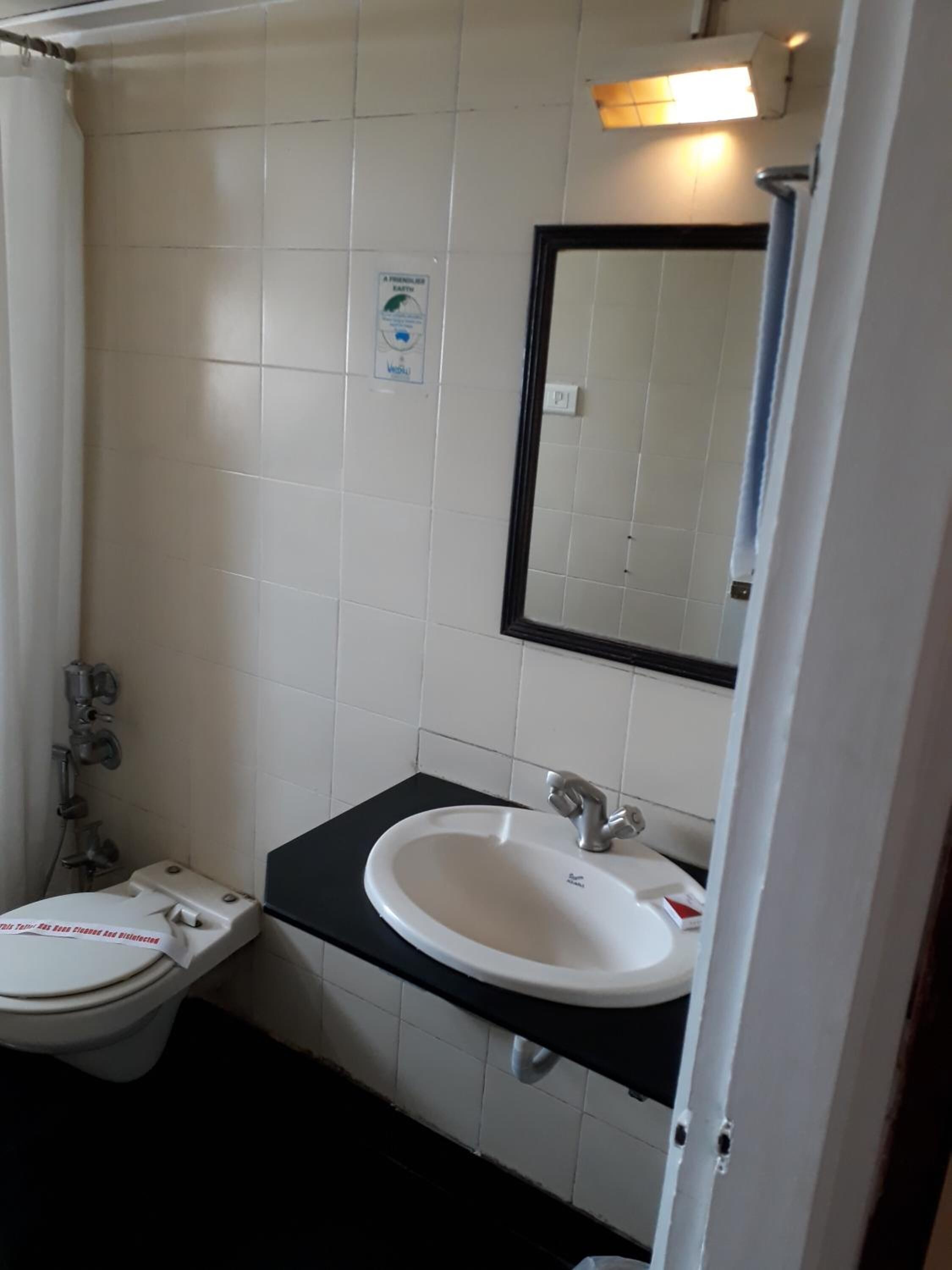 Un baño pequeño con inodoro blanco, un lavabo con encimera negra y un espejo sobre el lavabo.