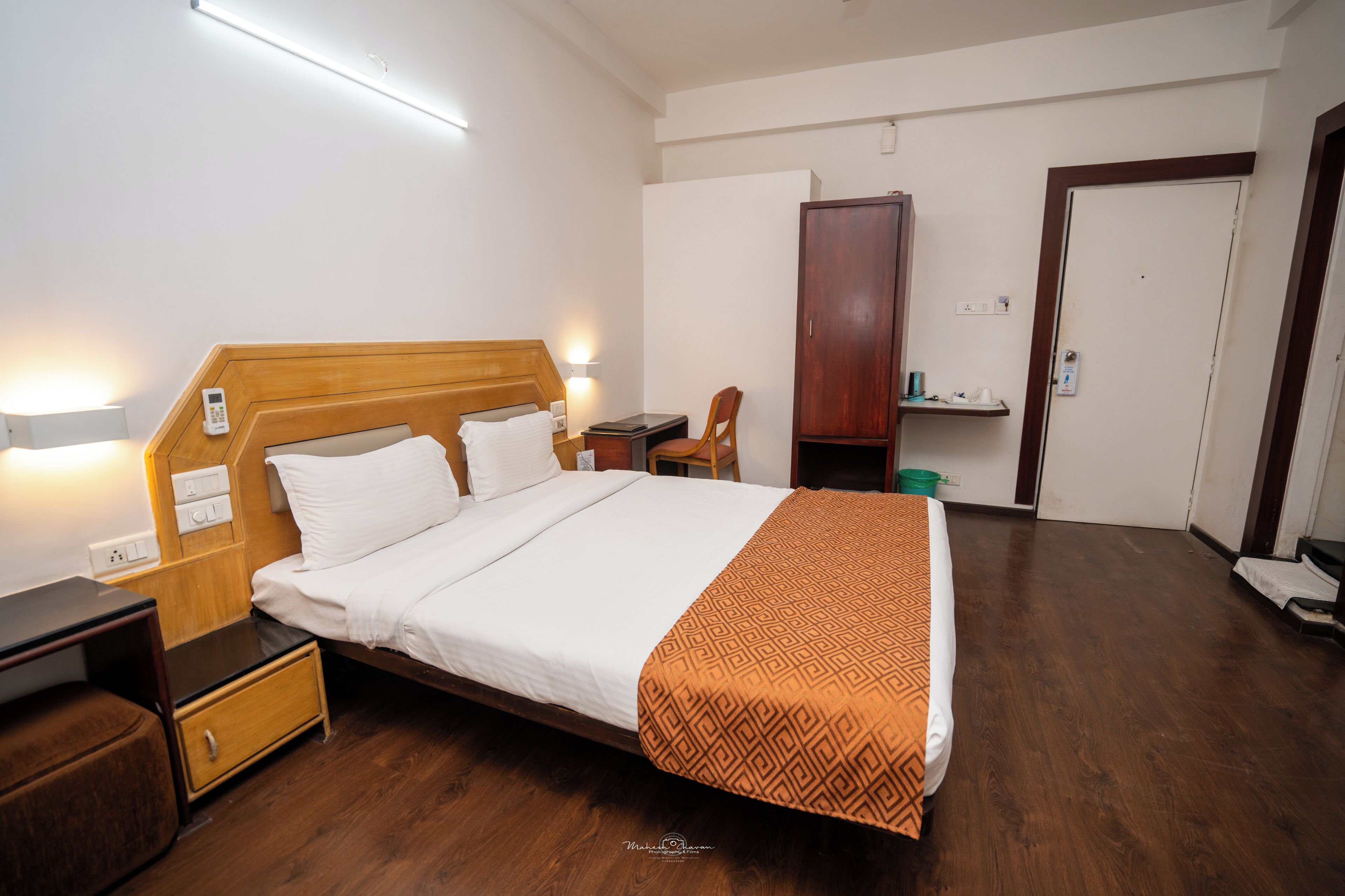 Una habitación de hotel con cama, mesita de noche, armario y una silla.