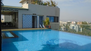 A rooftop swimming pool with a view of the cityscape. - Hotel Vrishali Executive Kolhapur (Kolhapur)