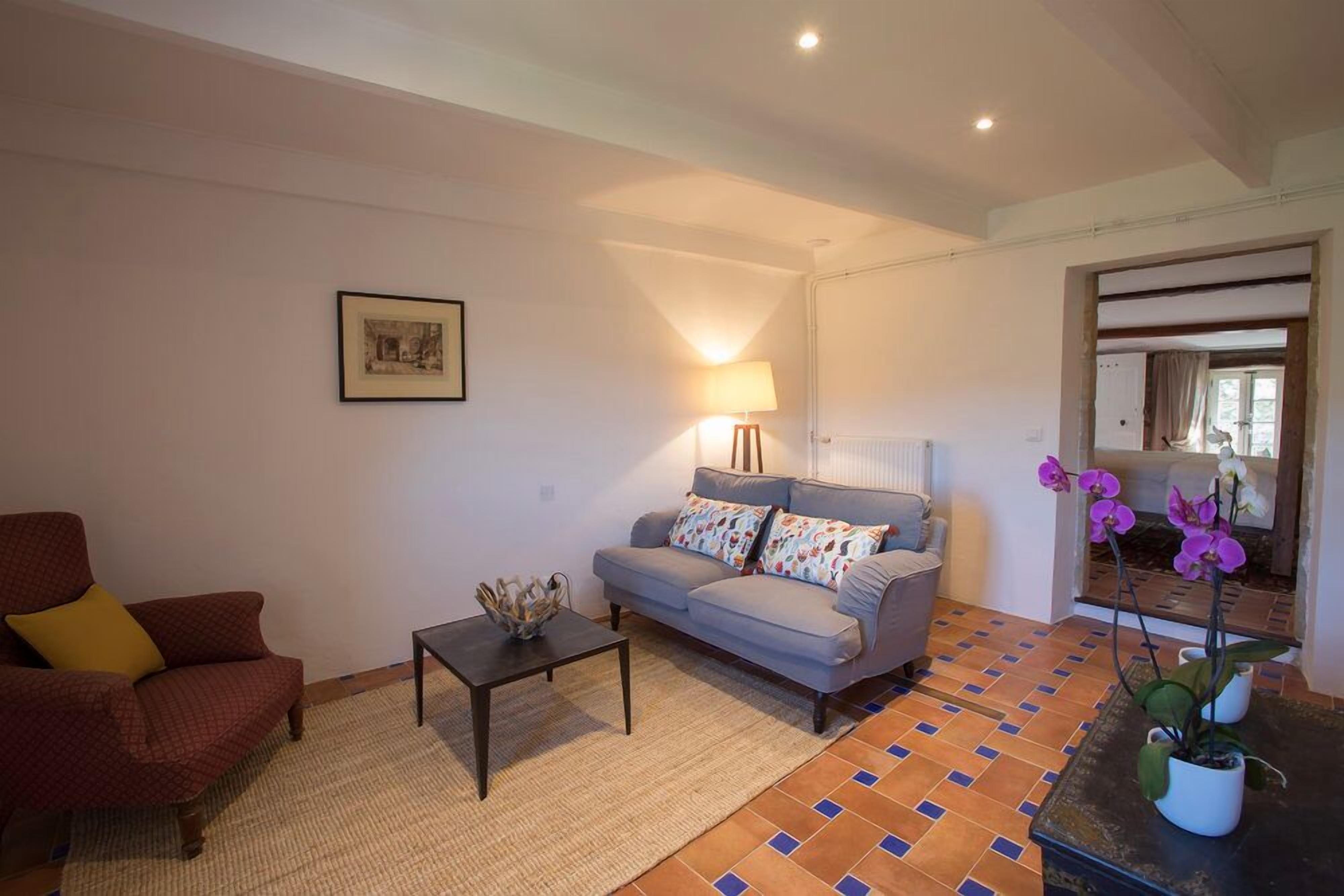 A living room with a sofa, armchair, coffee table, and a lamp.