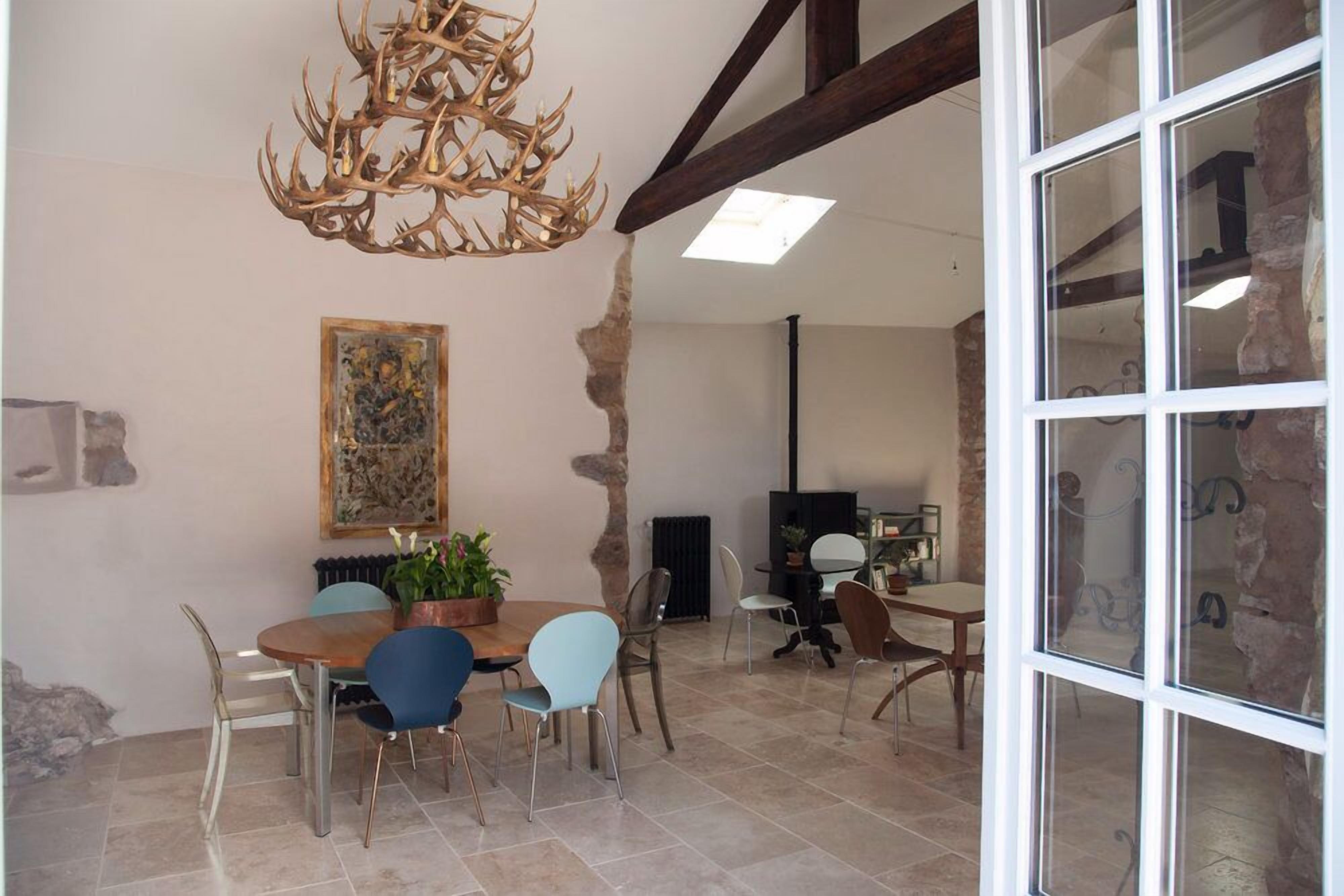Un coin repas avec une table ronde, des chaises, un lustre et un tableau au mur.
