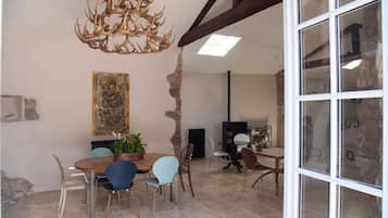 Un coin repas avec une table ronde, des chaises, un lustre et un tableau au mur.