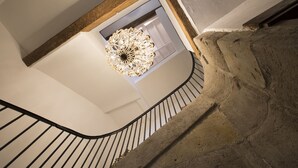 A staircase with a wrought iron railing, a stone wall, and a chandelier. - Chateau d'Olmet Guesthouse (Olmet-et-Villecun)