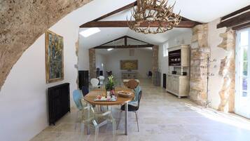 Un'ampia sala da pranzo con soffitto alto, pareti in pietra e un rustico lampadario.