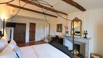 Une chambre spacieuse avec un grand lit, une cheminée et une poutre en bois au plafond.