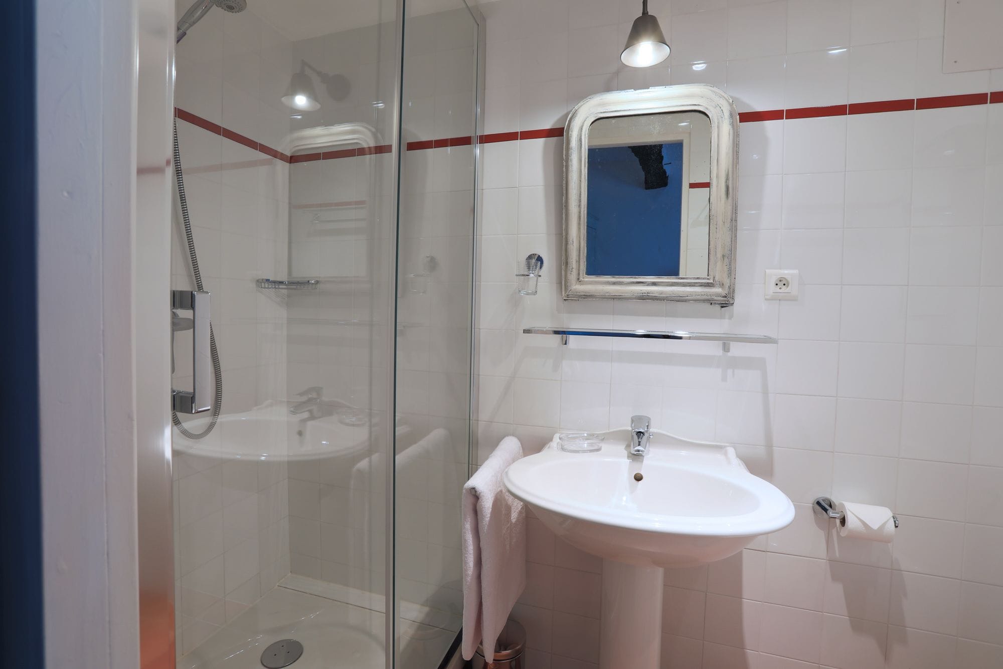 Une salle de bain moderne avec une douche à parois de verre, un lavabo blanc et un miroir au-dessus du lavabo.