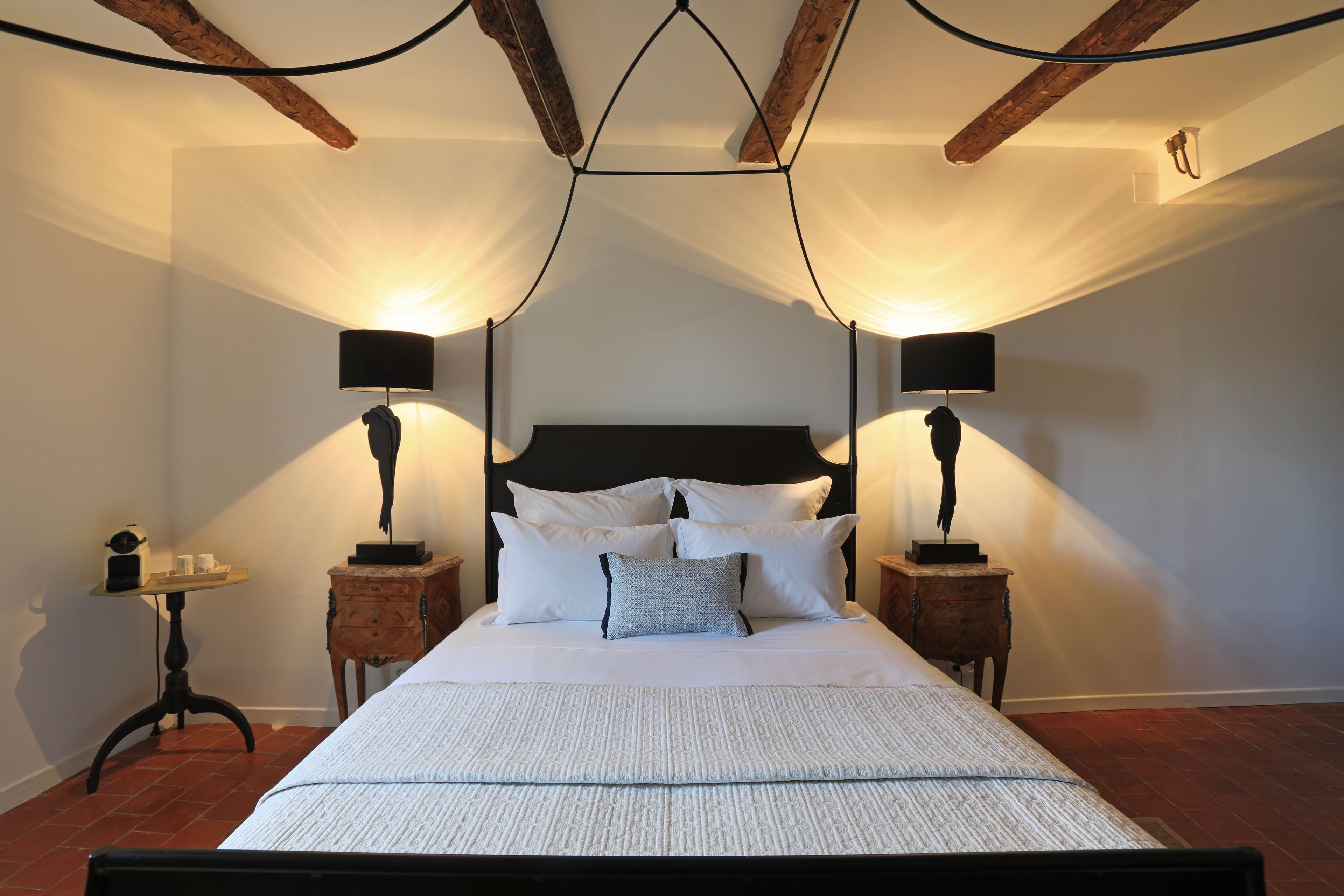 Een slaapkamer met een groot bed, twee nachtkastjes en een klein tafeltje met een lamp.