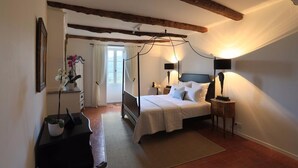 A bedroom with a four-poster bed, bedside lamps, a dresser, and a window with curtains. - Chateau d'Olmet Guesthouse (Olmet-et-Villecun)