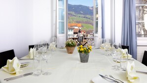 A dining table set for a meal with a view of a mountain landscape through an open window. - Hotel Kreuz by b_smart (Sachseln)