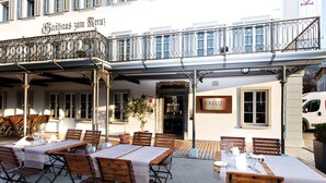 An outdoor café with wooden tables and benches, a sign reading "Kreuz," and a building with a balcony. - Hotel Kreuz by b_smart (Sachseln)