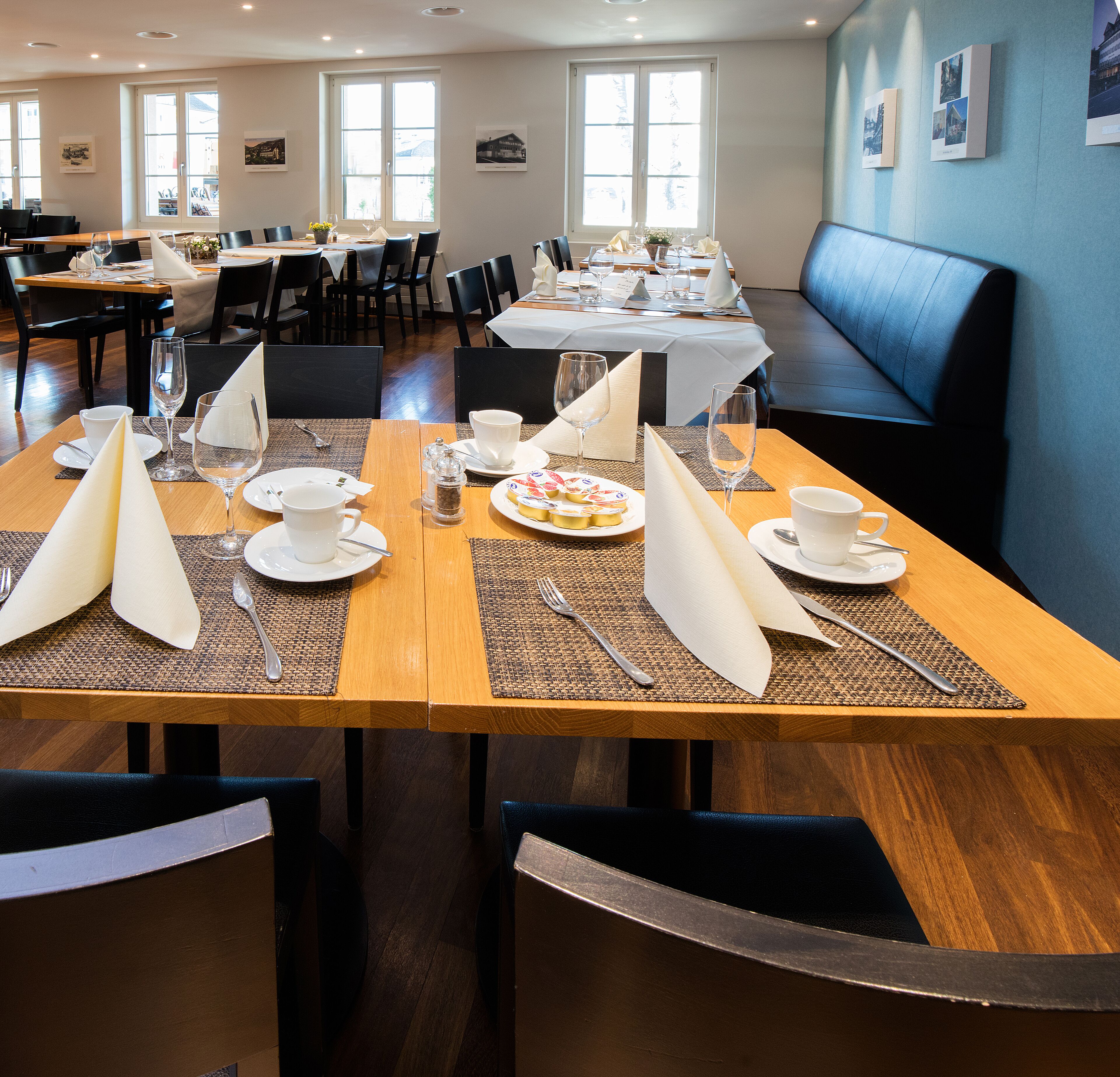 Un espace repas avec des tables mises pour le repas, comprenant des assiettes, des verres et des couverts.