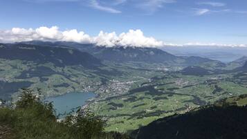 Une vue panoramique sur un paysage montagneux, avec un lac, des champs verdoyants et une petite ville.