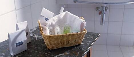 A bathroom with a marble countertop, a wicker basket with toiletries, a white towel, and a sink with a faucet.