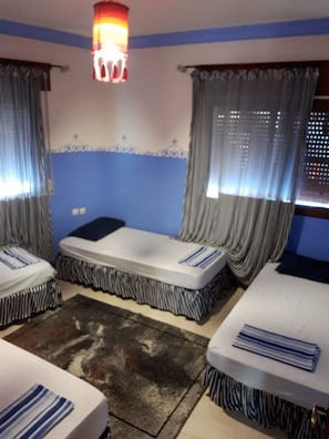 Una habitación con dos camas, un tapete estampado y cortinas.