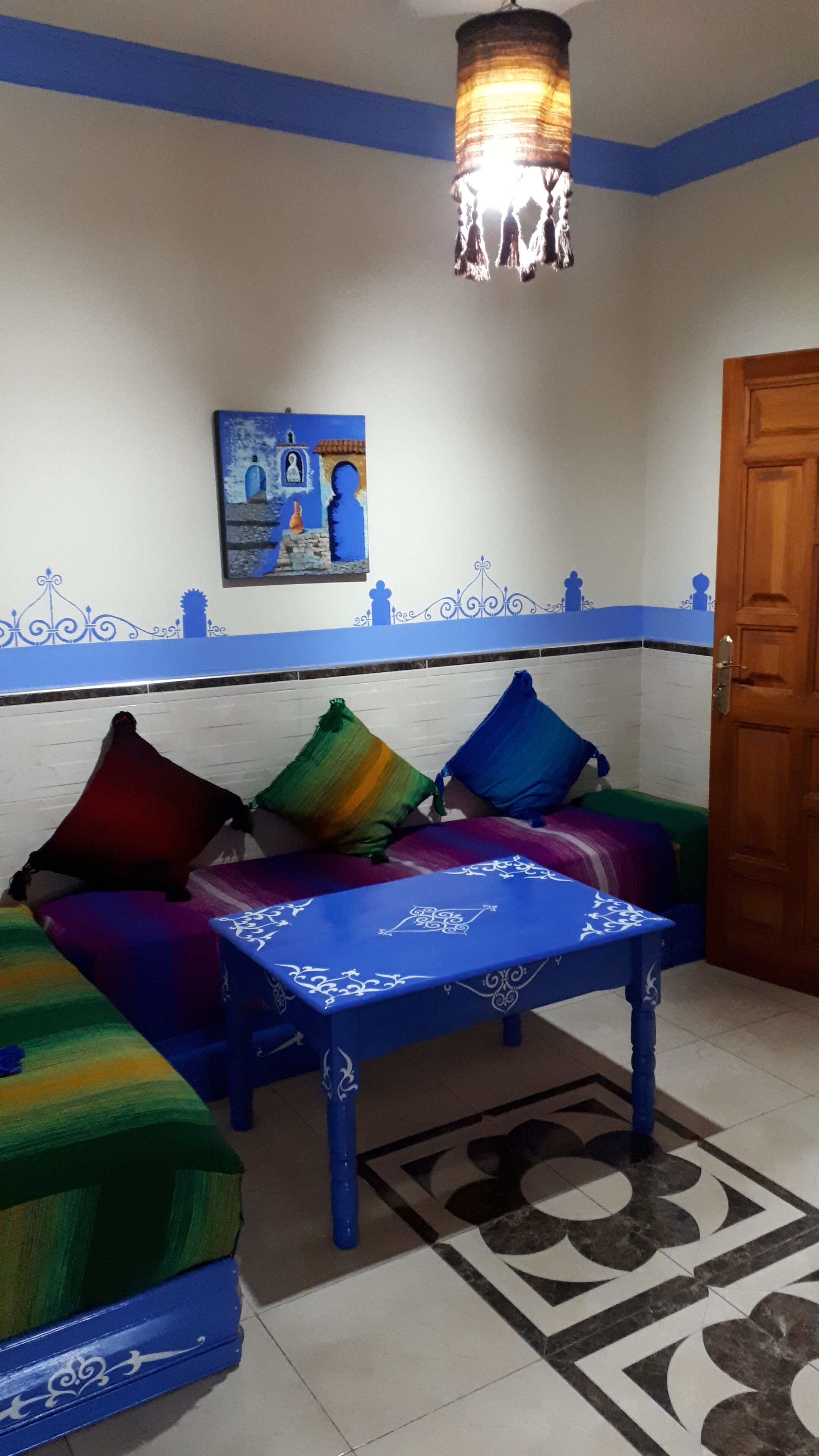 A room with a blue sofa set, a patterned table, and a decorative wall piece.