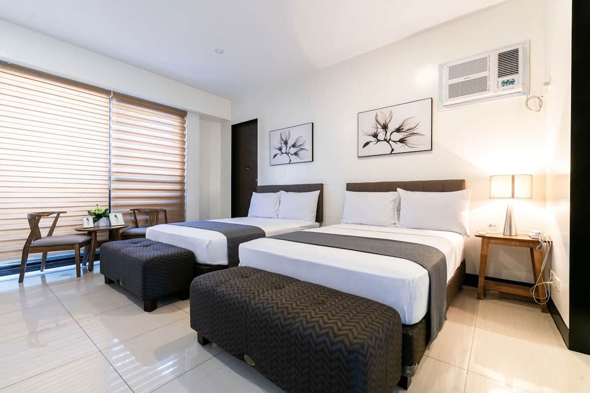 A hotel room with two beds, a desk, a chair, and artwork on the walls.
