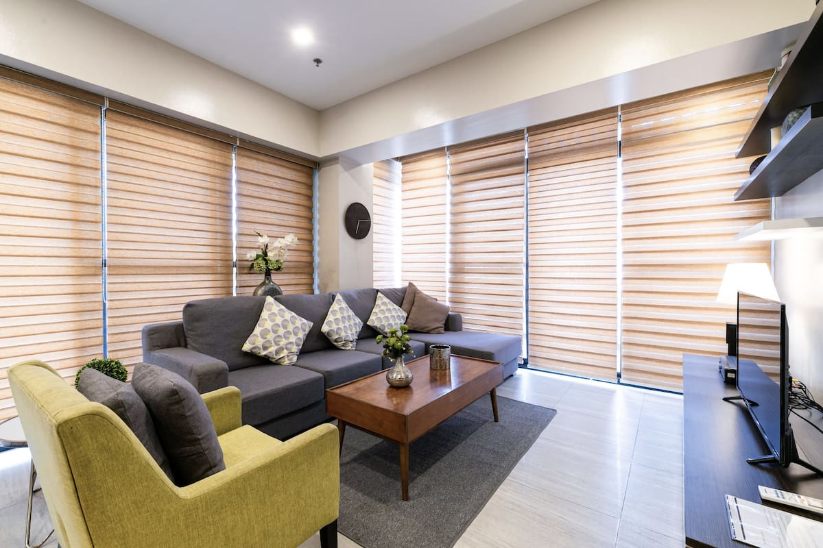 A modern living room with a sofa, armchairs, a coffee table, and a television.