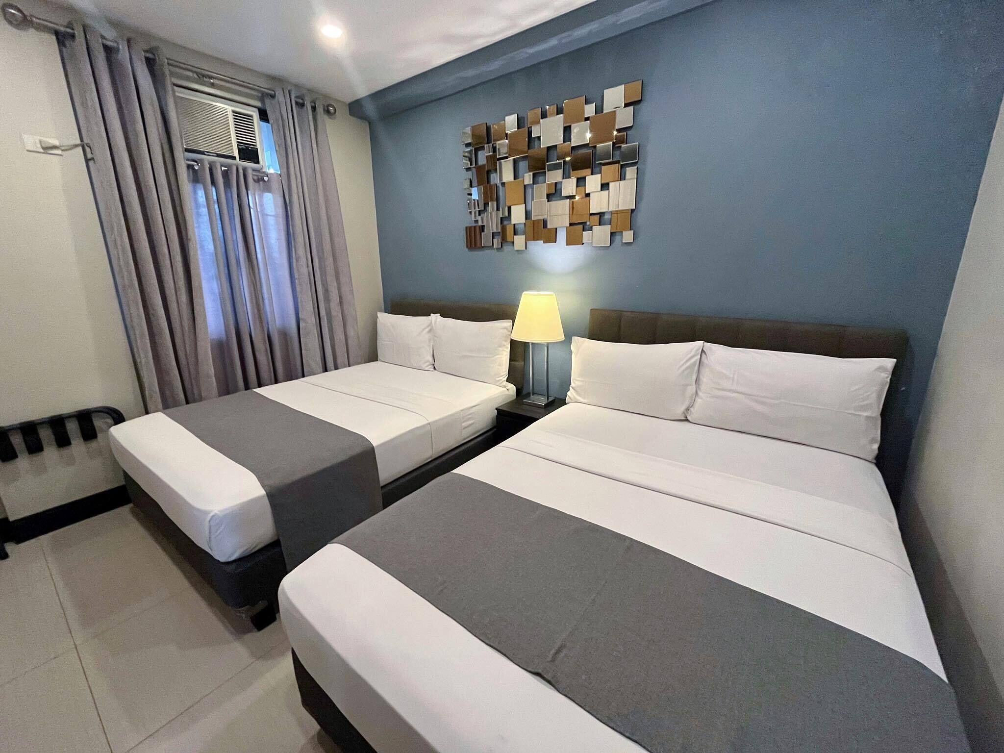 Una habitación de hotel con dos camas, una lámpara fijada a la pared y un adorno mural.