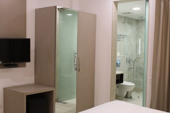 Un baño moderno con cabina de ducha de vidrio, inodoro y televisor montado.