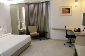 A hotel room with a bed, a chair, a desk, a television, and a bathroom. - Keys Lite by Lemon Tree Hotels, Mayfield, Gurgaon (Gurugram)