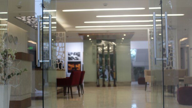 A modern lobby with glass doors, a reception desk, and a seating area with chairs and a table. - Keys Lite by Lemon Tree Hotels, Mayfield, Gurgaon (Gurugram)