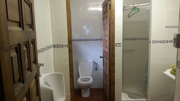 Et lille badeværelse med toilet, pissoir og bruseområde.