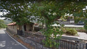 Un edificio in pietra con tetto in tegole rosse, un vialetto lastricato e un recinto in metallo.