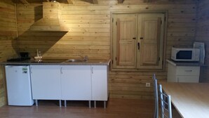 Una cucina compatta con pareti in legno, un lavandino, un forno a microonde e un frigorifero.
