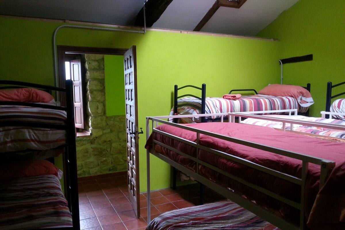 A dormitory room with bunk beds, a stone wall, and a window.