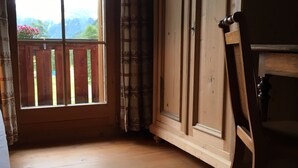 A room with a large window, wooden floor, and a wooden chair.