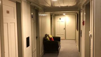 A hallway with carpeted floors, white doors, and a couch with pillows.