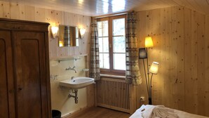 A wooden-paneled bathroom with a sink, mirror, and window.