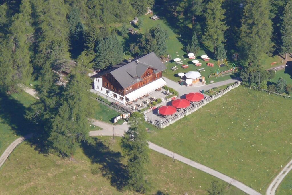 Eine Lodge mit einem großen Gebäude und einer Terrasse mit roten Sonnenschirmen.