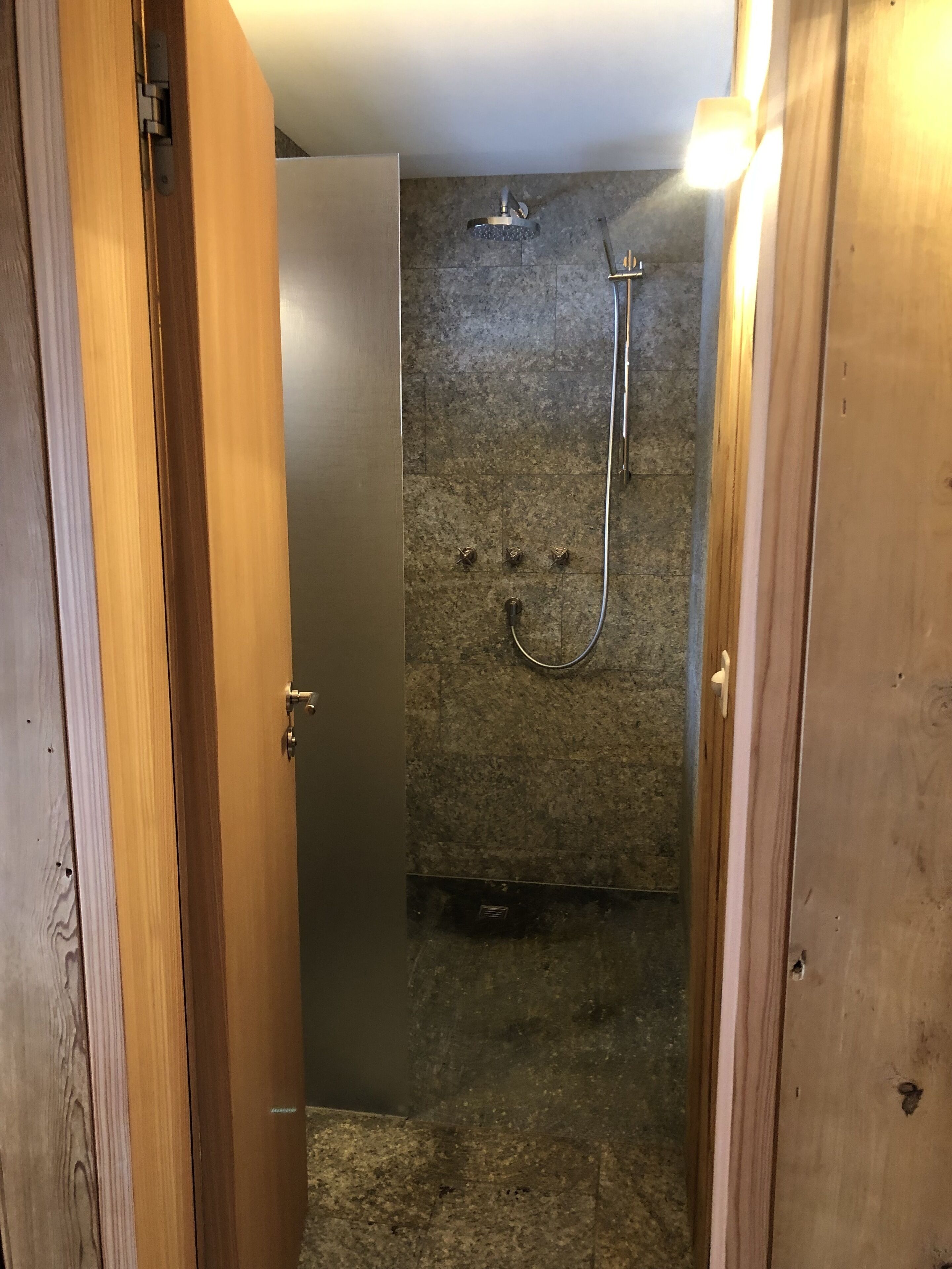 Un espacio de ducha con cabezal de ducha manual y grifo de pared.