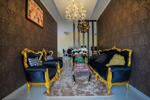 A luxurious room with two ornate black sofas with gold trim, a chandelier, and a patterned rug. - Sanur Cempaka Living (Denpasar)