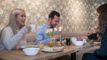 Un comedor con un fondo de papel tapiz floral, una mesa de madera y una vela.